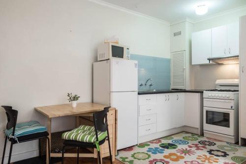 a kitchen with a table and a white refrigerator at Elwood Beach Apartment (2 min walk from beach) in Melbourne