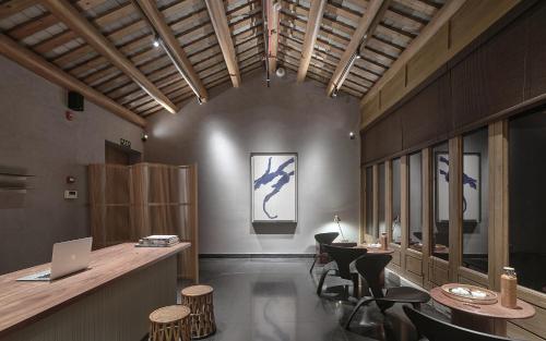a room with a table and chairs and a laptop at Jiangnan House Chaozhou in Chaozhou
