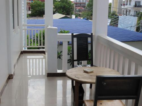 a porch with a wooden table and chairs on a balcony at The Blanc Residence in Siem Reap