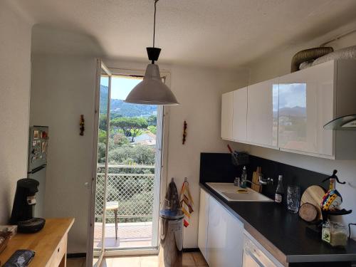 une cuisine avec des placards blancs et une vue sur un balcon. dans l'établissement La Pointe Rouge vue mer, à Marseille