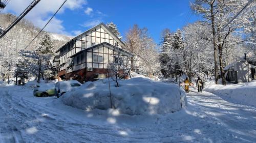 a snow covered street with a building in the background at Hotel Sejour Mint in Hakuba in Hakuba