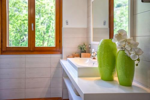 baño con lavabo y 2 jarrones verdes con flores en SARDINIA RE - Villa Martin Panoramic View, en Alghero