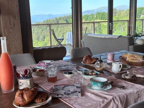 een tafel met ontbijtproducten en uitzicht op een berg bij Chalet La Petite Ourse in Hohrod