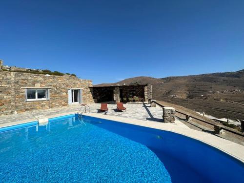 una piscina azul frente a una casa en Divine Blue Villa Nano in Koundouros Kea Cyclades with pool and sea view, en Koundouros