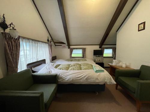 a bedroom with a bed and two chairs at Hotel Sejour Mint in Hakuba in Hakuba