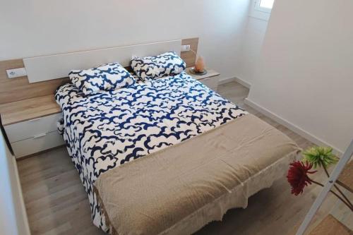 Schlafzimmer mit einem Bett mit blauer und weißer Bettwäsche und Kissen in der Unterkunft Piso nuevo a 2 minutos de la playa in Sant Feliu de Guixols