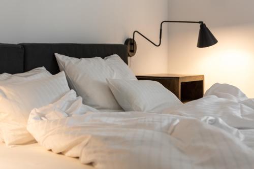 an unmade bed with white sheets and a lamp at Das Kubatzki in Sankt Peter-Ording
