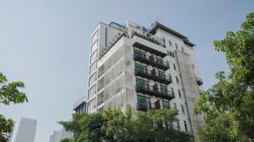 a tall white building with trees in front of it at Monsoon Bassac Hotel in Phnom Penh
