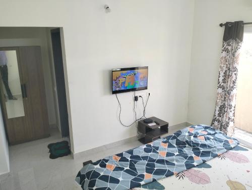 um quarto com uma cama e uma televisão na parede em Beach Dreamz Villa 2 BHK Near Pondy and Auroville em Marakkānam