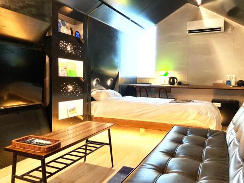 a bedroom with a bed and a couch and a table at ADLIV/Factry Stay/工場に泊まれる in Mima