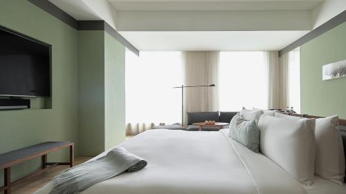 a bedroom with a large white bed with a flat screen tv at The Sukhothai Shanghai in Shanghai