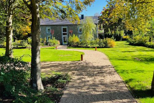 einen Gehweg vor einem Haus mit Bäumen und Gras in der Unterkunft Garden Lodge - Le Tulipier in Olne