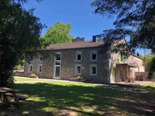 an old stone house with a picnic table in front of it at Jacuzzi - BBq - Jardin - Garden Lodge - Le Tulipier in Olne
