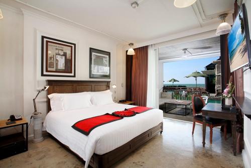 a bedroom with a bed and a desk and a balcony at Pattaya Modus Beachfront Resort in North Pattaya