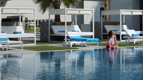 a woman sitting on the edge of a swimming pool at InterContinental Bahrain by IHG in Manama
