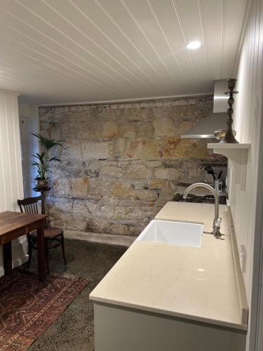 a kitchen with a sink and a stone wall at Lumeah - Servant Quarters in Hobart