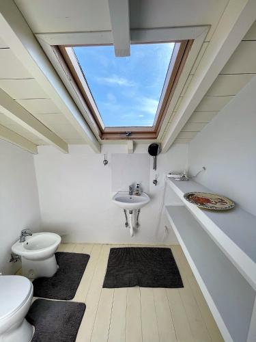 a bathroom with a toilet and a sink and a skylight at Thymari House in Milia
