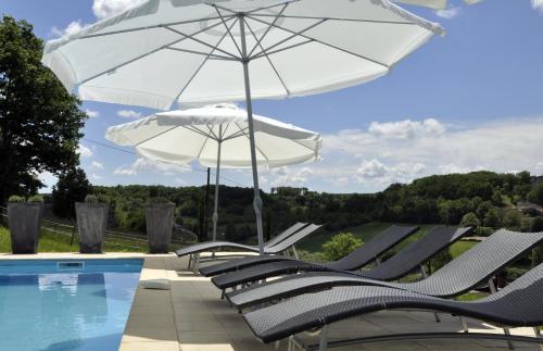 a group of chairs and an umbrella next to a swimming pool at Le Relais de Roquefereau in Penne-dʼAgenais