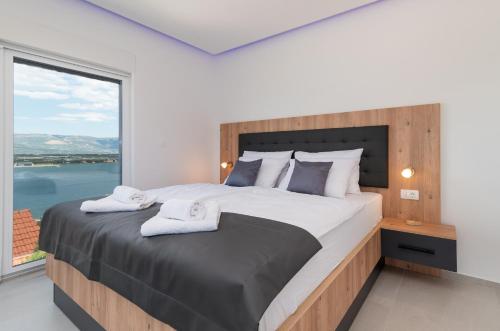 1 dormitorio con 1 cama grande y ventana grande en Luxury Villa Sun Stone heated pool & whirlpool, en Trogir