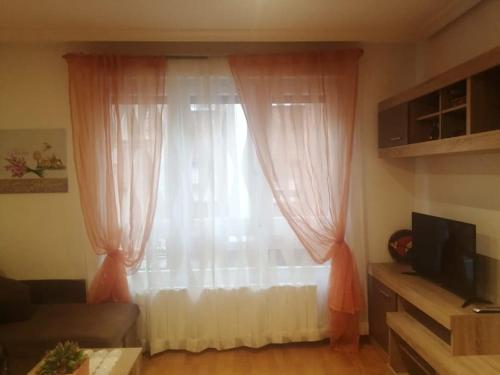 a living room with a window with pink curtains at Apartamento con terraza a 800 m playa in Gijón
