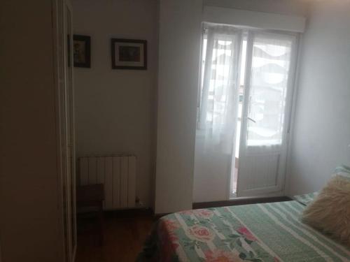 a bedroom with a bed and a door with a window at Apartamento con terraza a 800 m playa in Gijón