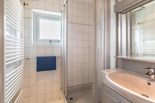 uma casa de banho branca com um lavatório e um espelho em Ferienhaus Herich em Nieblum