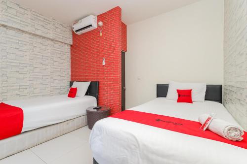 2 camas en una habitación con una pared de ladrillo rojo en RedDoorz Syariah near Green Park Jatiwarna, en Bekasi