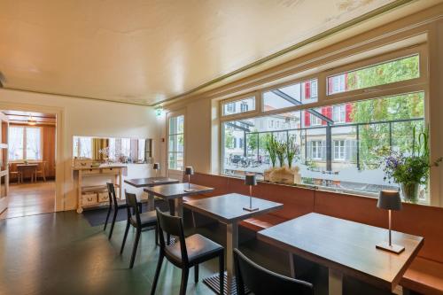 um restaurante com mesas, cadeiras e janelas em Linde Heiden Swiss Quality Hotel em Heiden