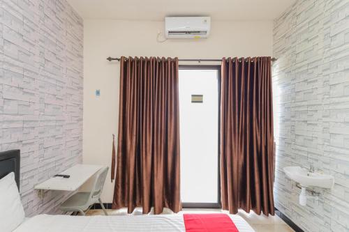 a bedroom with a bed and a sink and a window at RedDoorz Syariah near Green Park Jatiwarna in Bekasi
