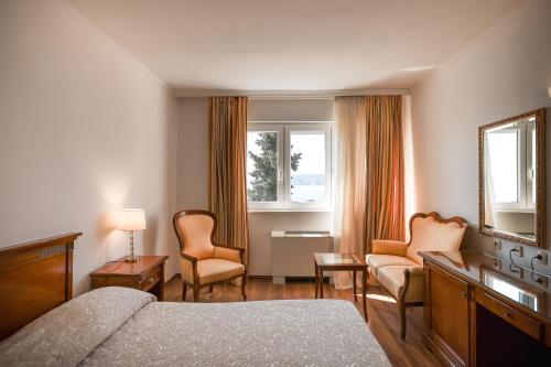 ein Hotelzimmer mit einem Bett, Stühlen und einem Spiegel in der Unterkunft Hotel Val in Trogir