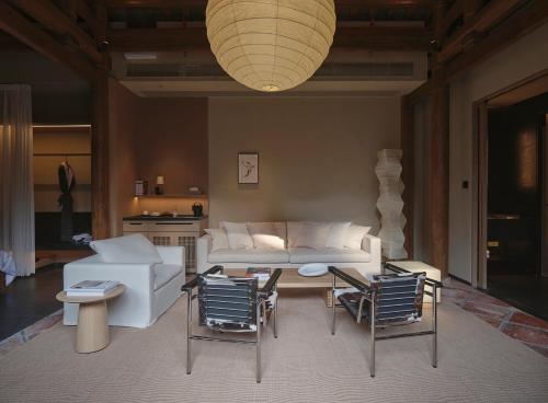 a living room with a white couch and chairs at Jiangnan House Chaozhou in Chaozhou