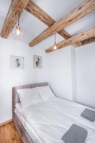 a bedroom with a bed with white sheets and wooden ceilings at Apartament Nowy Świat 2 in Gliwice