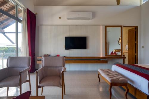 a hotel room with a bed and two chairs and a television at Beacon By The Bay Villas and Suites by the Clarks in Matara