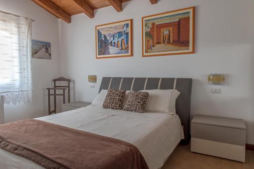 1 dormitorio con 1 cama con 2 cuadros en la pared en Countryside villa with pool en San Sperate
