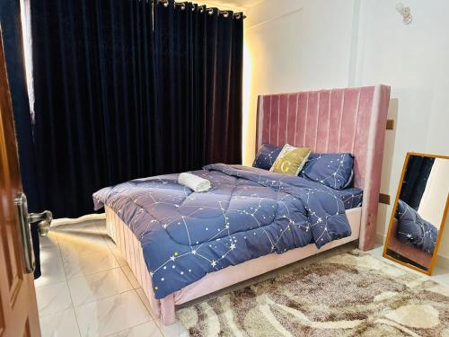 a bedroom with a bed with blue comforter and yellow pillows at Lakira Nita's place in Nairobi