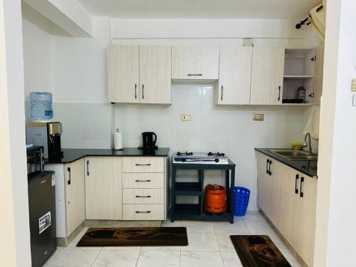 uma pequena cozinha com armários brancos e um fogão em Lakira Nita's place em Nairobi