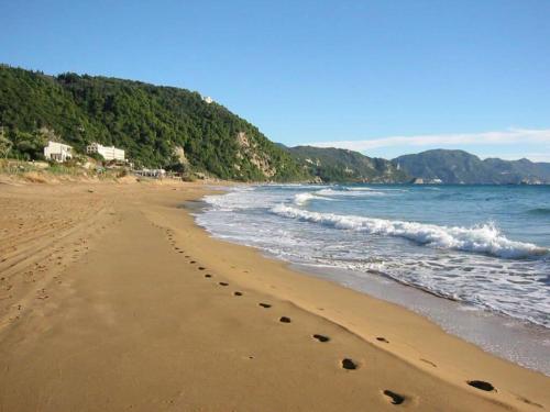 a beach with footprints in the sand and the ocean at Kanakades Valley View House in Kanakádes
