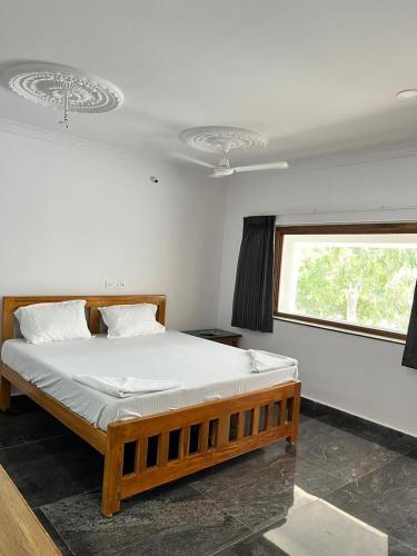 a bedroom with a wooden bed in a room with a window at ANAND Beach Guesthouse by Moonrocks in Mahabalipuram