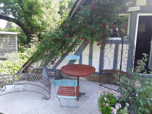 a patio with two benches and a table and flowers at Un week-end à la campagne in Pont-Audemer