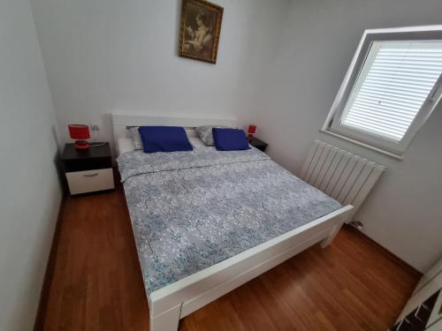 a bedroom with a bed with blue pillows and a window at Apartments Katarina in Šmrika