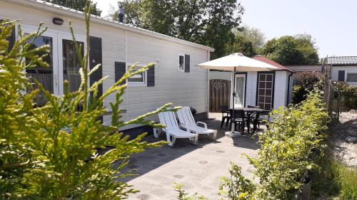 a patio with two chairs and a table and an umbrella at Stellechalets op Vakantiepark Stelleplas - Heinkenszand in Heinkensand