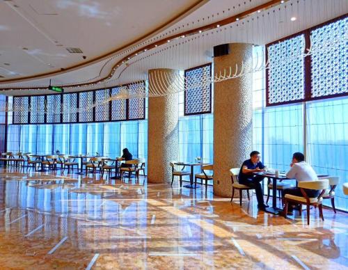 a lobby with people sitting at tables in a building at Days Hotel & Suites China Town---Five minutes to reach Changsha Station, the metro Line 2 & Line 6 are nearby,free gym & laundromat,Chinese and Western buffet breakfast is offered on the 31st floor in Changsha