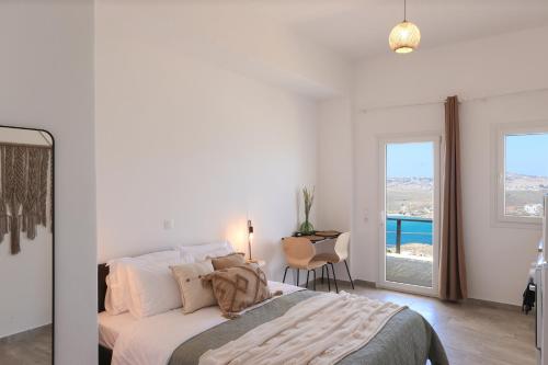 1 dormitorio con cama, mesa y ventana en ēnNĒ Studios for Views & Tranquility, en Ftelia
