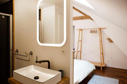 ein Badezimmer mit einem Waschbecken neben einem Bett in der Unterkunft Gîte Belle Vue in Alise-Sainte-Reine