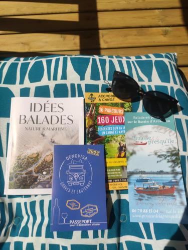 a pile of books sitting on top of a bed at CAP FERRET L'escale Mobil-home 6 personnes in Lège-Cap-Ferret