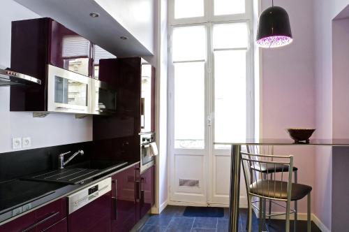 une cuisine avec des placards violets et un comptoir noir dans l'établissement Louis Combes - Localisation exceptionnelle 1 chambre parking, à Bordeaux