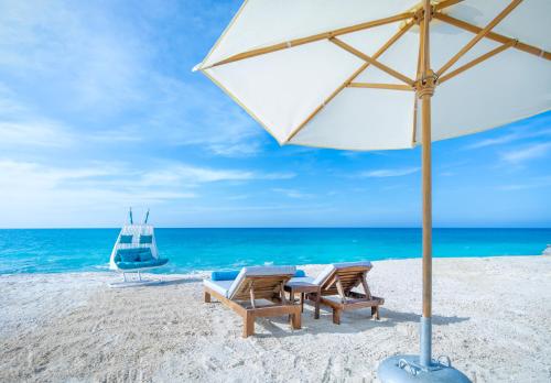 - deux chaises et un parasol sur la plage dans l'établissement X Eastern Sidi Abdel Rahman Hotel, à El Alamein