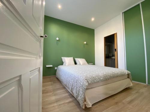 Un dormitorio con una cama y una pared verde. en Appartement luxueux rénové avec balcon & garage, en Troyes