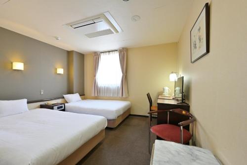 a hotel room with two beds and a desk and a chair at Wakayama Daini Fuji Hotel in Wakayama