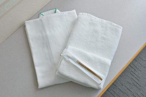 a pair of white towels sitting on top of a table at Wakayama Daini Fuji Hotel in Wakayama